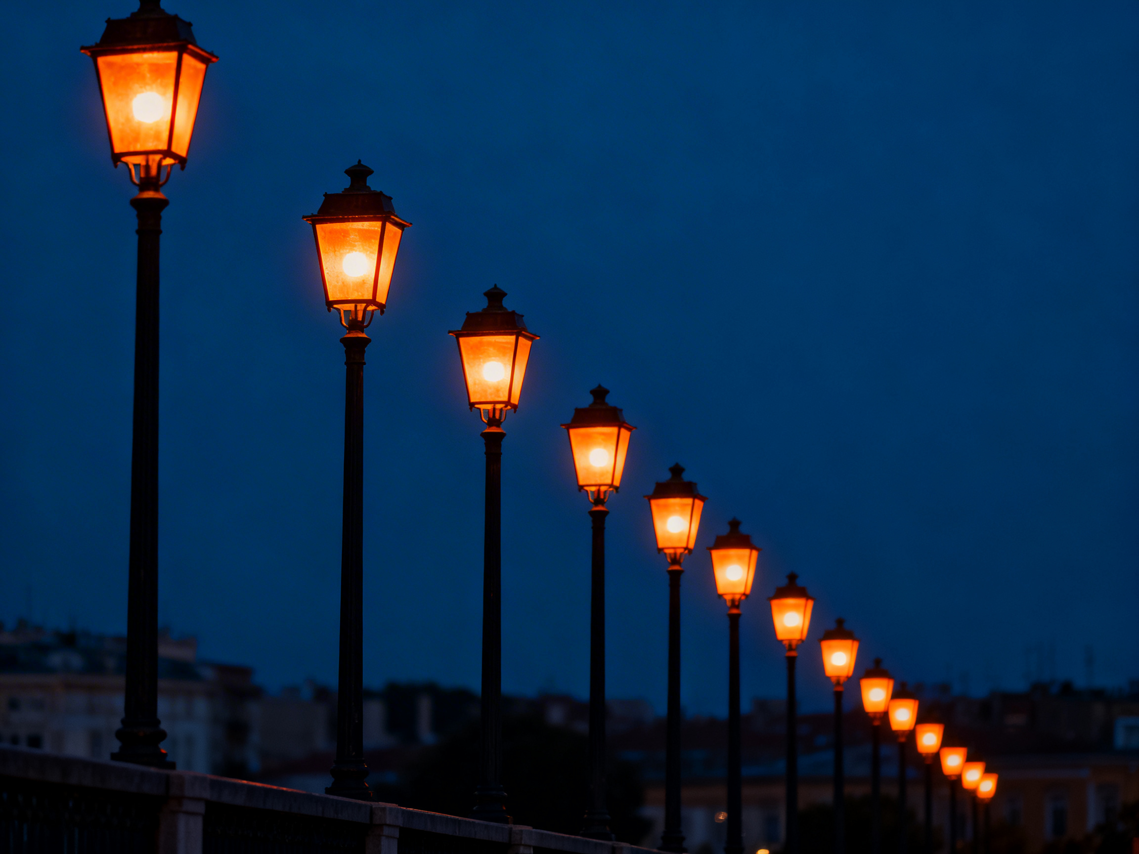 图中展示了一排在夜色中延伸的复古路灯，背景是深蓝色的夜空。画面构图采用了极具纵深感的对角线排列，路灯由左前方近处向右后方远处依次排开，体积逐渐缩小，营造出一种深远的视觉效果。路灯呈现经典的欧式造型，黑色的金属灯柱支撑着六角形的灯罩，灯罩内散发出温暖而明亮的橙黄色光芒，与冷色调的背景形成鲜明对比。

在画面的左下角，可以看到模糊的城市建筑轮廓和桥梁护栏。作为一张 AI 生成的图片，画面存在明显的逻辑缺陷：这一长排路灯的间距异常密集，且全部悬浮或竖立在一条极窄且透视不自然的边缘上，缺乏合理的地面支撑结构。此外，远处的灯柱在缩小过程中出现了线条扭曲，最远端的几盏灯光影表现过于简化，缺乏真实环境中的光线衰减细节。