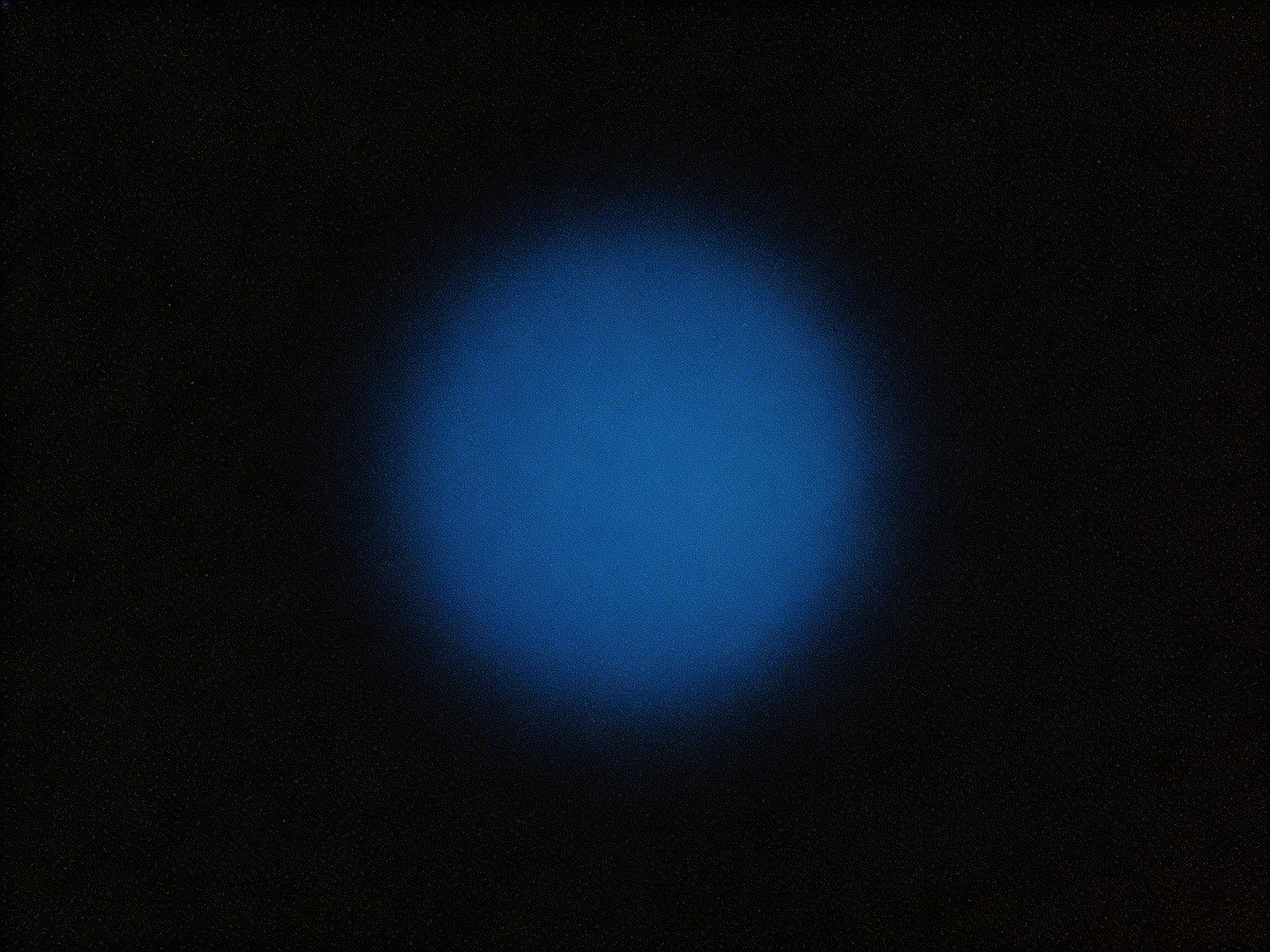 图中展示了一个极简主义的抽象场景。在纯黑色的背景中心，悬浮着一个巨大的蓝色圆形光斑。这个圆形的边缘非常模糊，呈现出一种向外扩散的柔和渐变效果，从中心的深蓝色逐渐过渡到边缘的暗蓝色，最终融入背景的黑暗中。整张图片布满了非常细密且均匀的噪点颗粒，这种质感让画面看起来像是老式胶片摄影或是带有电子干扰的屏幕截图。从 AI 生成的角度来看，这张图片结构过于单一，缺乏具体的细节层次，圆形的边缘过渡虽然平滑，但整体构图显得有些空洞。画面中没有明确的光源方向，这种完全对称的布局在视觉上略显机械，缺乏自然光影的灵动感。