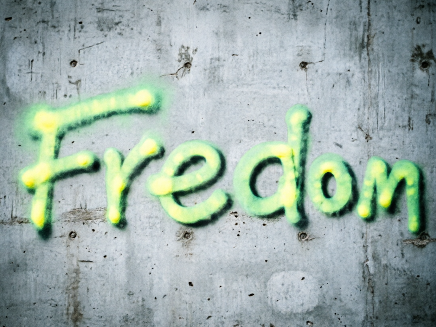 图中展示了一面粗糙的灰色混凝土墙壁，墙面上有一处醒目的喷漆涂鸦。涂鸦使用了明亮的荧光绿色，边缘带有淡黄色的高光，呈现出一种模糊且具有发散感的喷涂质感。墙体本身布满了细微的裂纹、深色的小孔和不规则的污渍，整体色调偏冷，营造出一种工业或街头废墟的氛围。构图简洁，文字位于画面中心。然而，这张 AI 生成的图片存在明显的拼写错误：涂鸦本意似乎是想表达“自由”（Freedom），但画面中显示的字母序列为“Fredom”，缺少了一个关键的字母“e”。此外，字母的笔画粗细不均，部分连接处显得生硬且不符合真实的喷漆流向，墙面的纹理在字母边缘处也显得有些不自然的平滑。