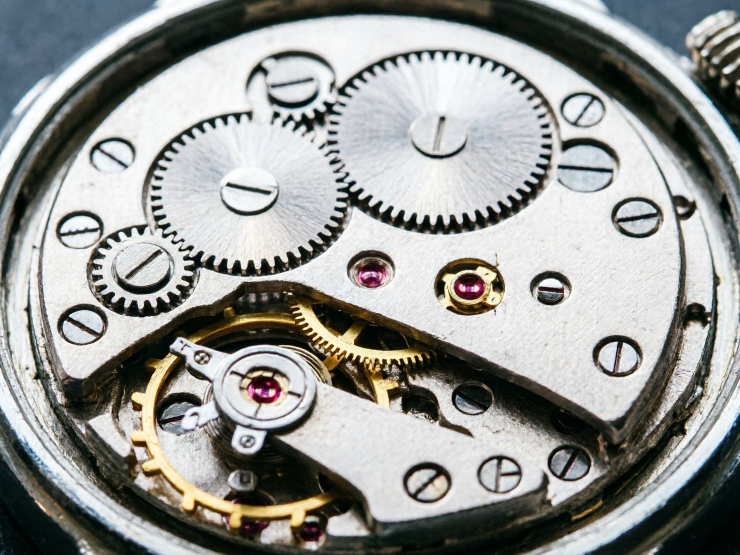 图中展示了一枚机械手表内部机芯的特写镜头。画面以银灰色和金属质感为主，错落有致地排列着多个大小不一的齿轮、螺丝和金属夹板。在机芯的下半部分，可以看到金色的摆轮和几颗闪烁着深红色的红宝石轴承，为冰冷的金属色调增添了视觉亮点。构图采用了俯视微距视角，细节丰富，展现出一种工业机械的美感。然而，画面中存在明显的 AI 生成缺陷：位于左上方的两个大齿轮边缘咬合逻辑混乱，齿尖形状不规则且相互重叠；部分螺丝的槽口方向和深度显得生硬且不自然；金属夹板的边缘切割处出现了模糊和结构断裂，缺乏真实机械应有的严丝合缝感。整体透视在边缘位置略显扭曲，使得机械结构看起来缺乏实际运作的物理逻辑。
