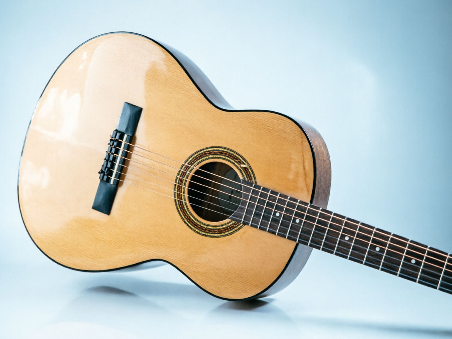 图中展示了一把斜放在浅蓝色背景前的古典吉他。吉他的面板呈现出明亮的浅木色，表面带有细腻的木质纹理和光滑的反光，琴身侧边则为深棕色。构图上，吉他的琴身占据了画面左侧的大部分空间，琴颈向右下方延伸。音孔周围装饰有精致的环状花纹，琴弦在光线下清晰可见。然而，画面中存在明显的 AI 生成缺陷：最显著的是琴弦逻辑混乱，琴弦在经过音孔后并没有整齐地连接到下方的琴码上，而是出现了断裂、交错和数量不一致的情况；琴码的形状扭曲且模糊，缺乏真实的物理结构；此外，琴颈上的品柱分布不均，且琴弦在指板上的排列显得非常杂乱，不符合乐器的实际构造。整体光影虽然柔和，但这些结构性的错误揭示了其 AI 生成的本质。