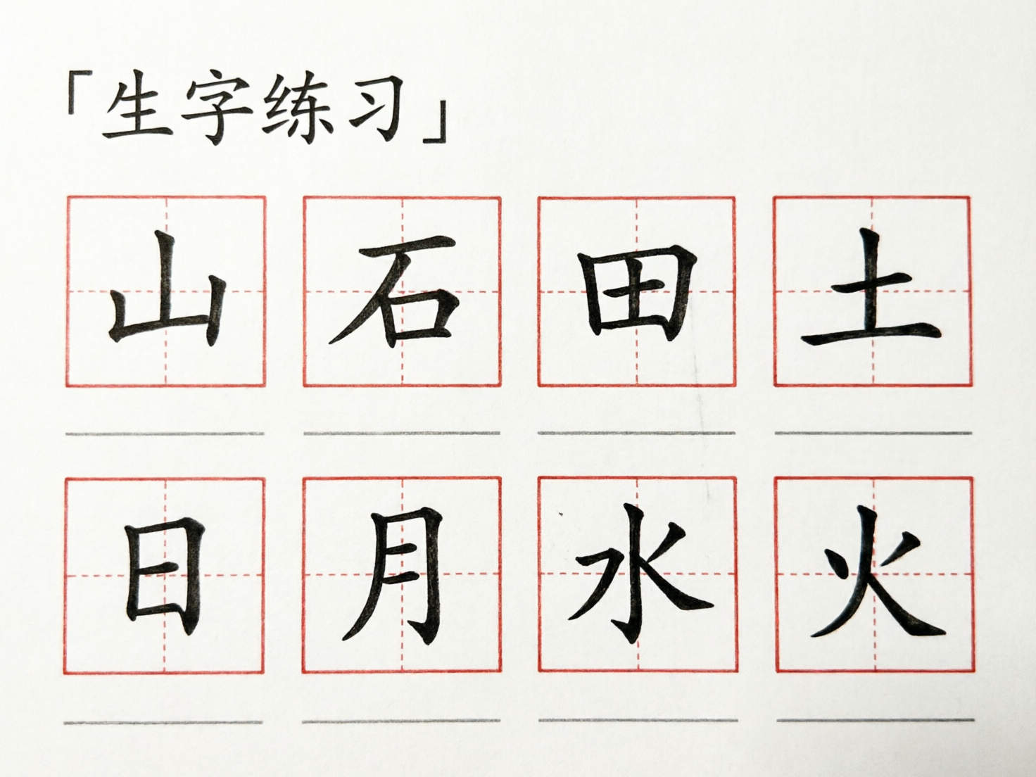画面中展示了一张模拟汉字书法练习帖的白底图片。顶部左侧印有黑色的「生字练习」四个大字，并带有直角引号。下方排列着两行、每行四个的红色田字格，每个格子内都有一个黑色的楷体汉字。第一行依次是「山、石、田、土」，第二行依次是「日、月、水、火」。每个田字格下方都有一条灰色的横线，用于临摹练习。

作为一张 AI 生成的图片，画面中存在一些明显的逻辑与细节缺陷。首先，顶部标题的右引号位置过低，且形状与左引号不完全对称。其次，田字格内的汉字虽然清晰，但部分笔画的粗细过渡略显生硬，缺乏真实毛笔书写的自然韵味。最明显的错误在于，第二行「日」字下方的灰色横线与田字格的间距，明显比其他汉字下方的间距要窄，导致视觉上的排版不整齐。此外，纸张背景过于纯净，缺乏真实的纸张纹理感。
